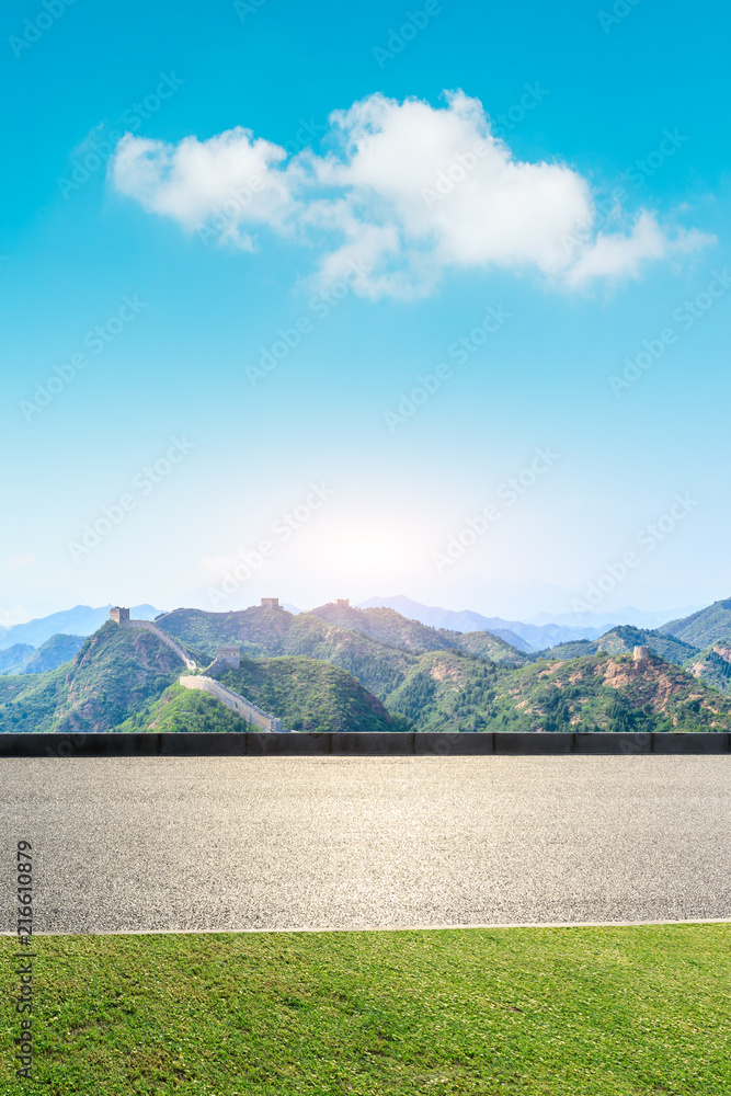 Empty asphalt road and great wall with mountains under the blue sky