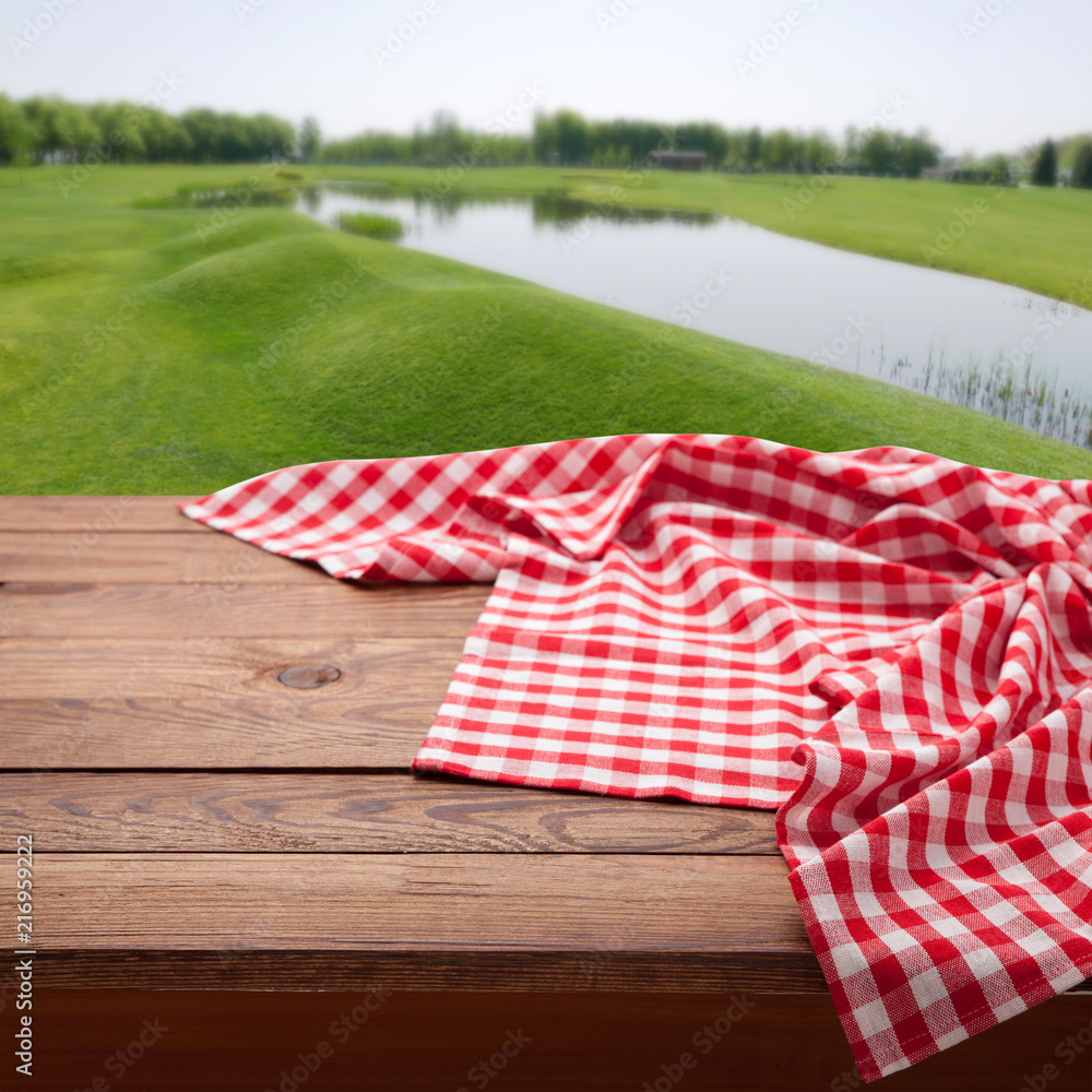 木质桌子上的红色方格桌布。餐巾特写俯视模型。夏季乡村背景