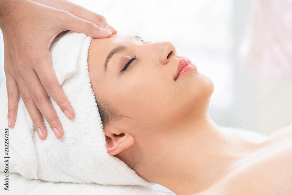 放松的女人在水疗中心接受面部和头部按摩。