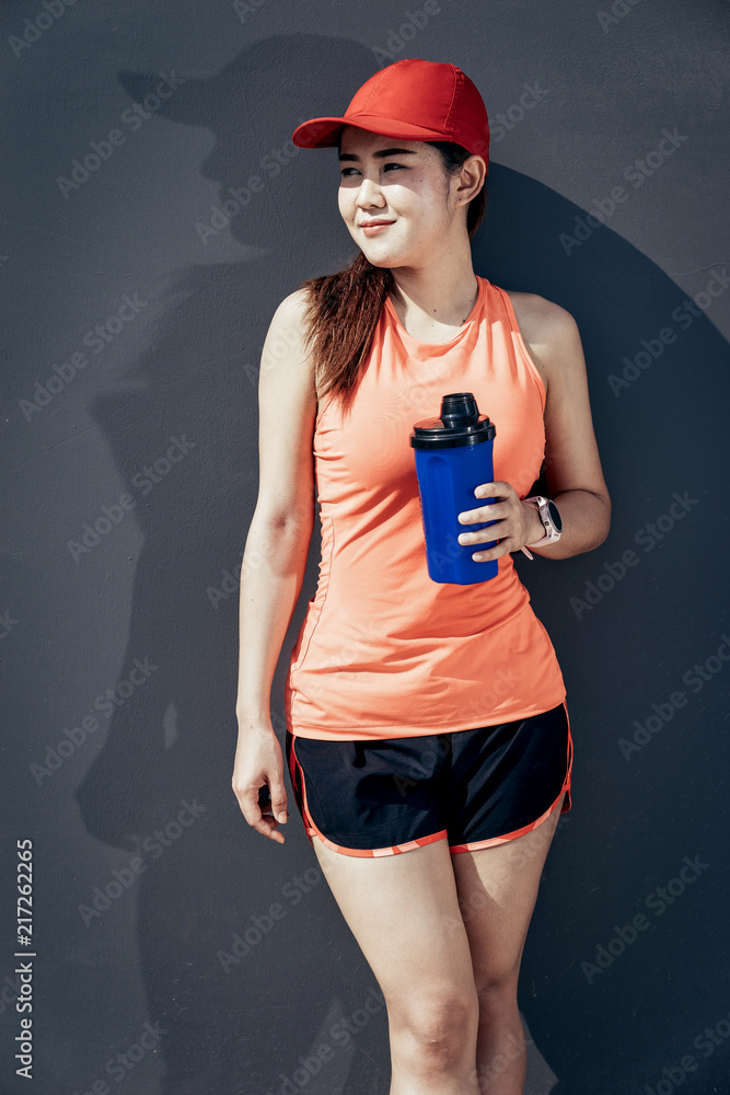 一名亚洲女运动员在水泥路上慢跑，她正在温暖自己的身体，为自己的tyi做准备