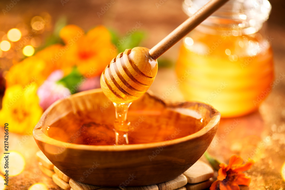 蜂蜜。健康的有机稠蜂蜜从木碗里的蜂蜜勺里滴下来。甜甜点回来了