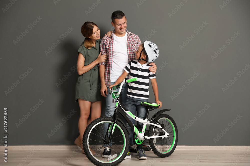 Portrait of parents and their son with bicycle near color wall