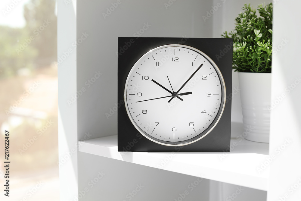 Analog clock on shelf indoors. Time of day