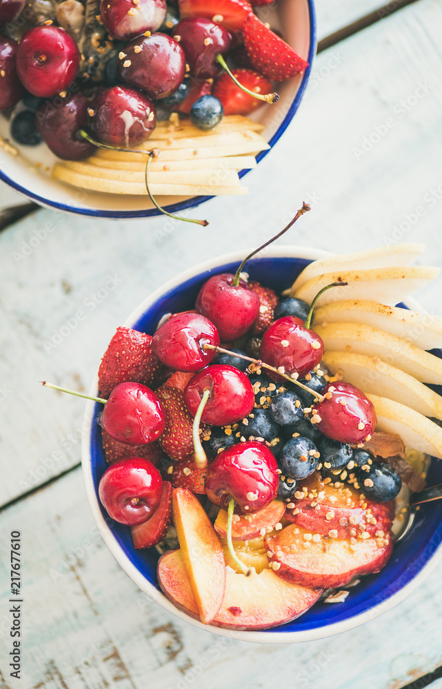 Healthy breakfast smoothie bowl with fresh fruit and berries, bee pollen and honey on blue table bac