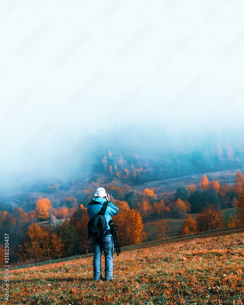 摄影师拍摄雾蒙蒙的山峰和橙色树木的秋季景观。乌克兰喀尔巴阡山