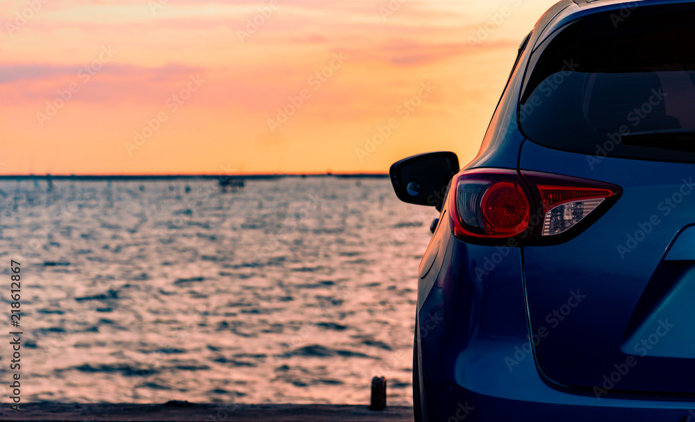 日落时分，蓝色紧凑型SUV汽车停在海边的水泥路上，具有运动和现代设计。Envi