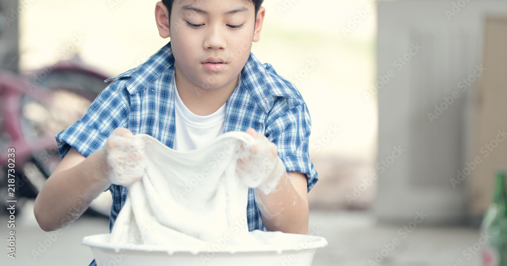 亚洲男孩用手洗毛巾。