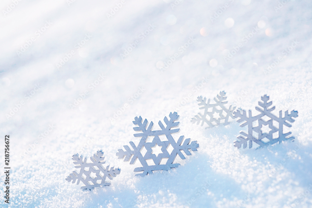 柔和的圣诞背景。装饰性雪花在雪中特写，在大自然的光线中