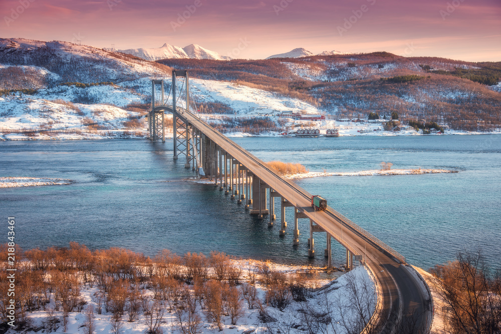 挪威罗弗敦群岛日落时的美丽桥梁。空中冬季景观，车在上面