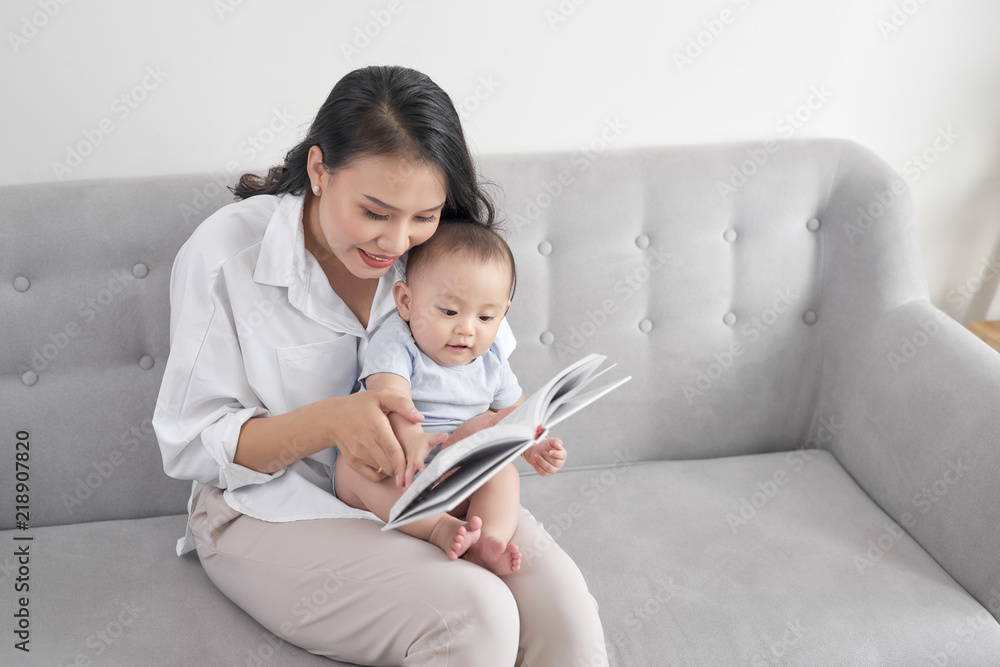 年轻的亚洲妈妈给宝宝读书。甜蜜的时刻。