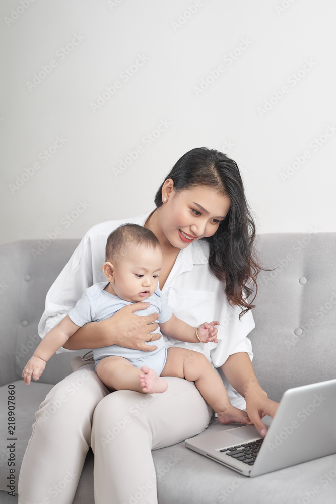 年轻母亲在家庭办公室工作时抱着孩子
