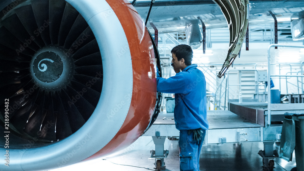 飞机维修技工在机库检查和调整飞机发动机。