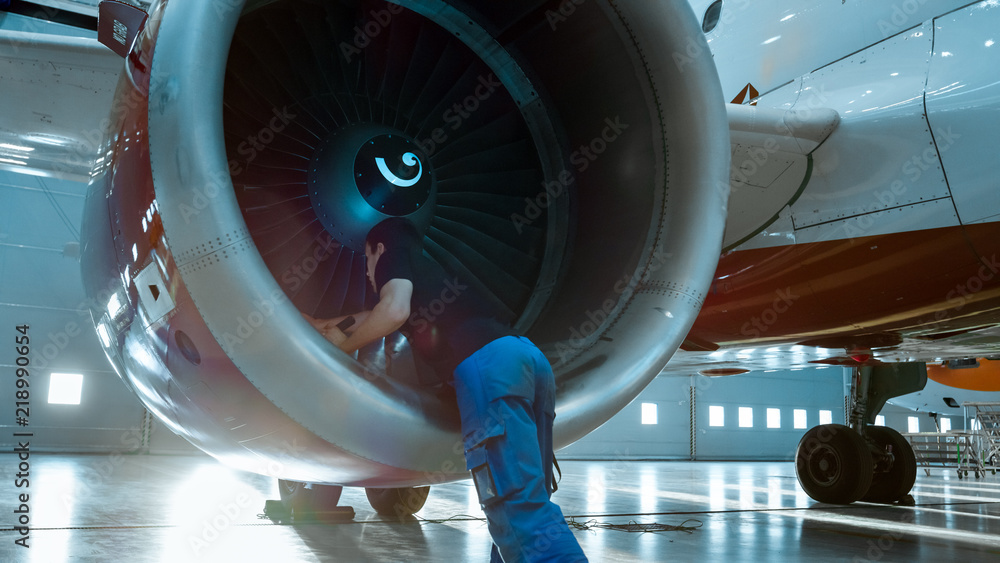 在机库里，飞机维修工程师/技术员/机械师用手电筒检查飞机