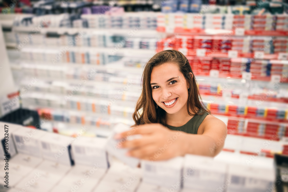 Young woman holding cosmetics in her hand in supermarket.