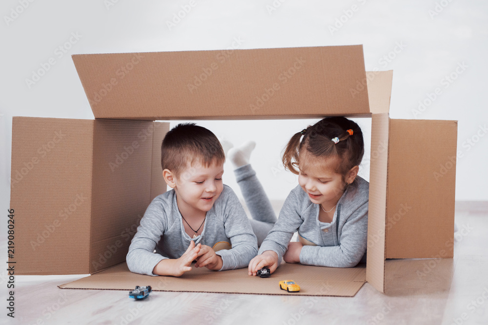 两个小孩男孩和女孩在纸板箱里玩小汽车。概念照片。孩子们有f