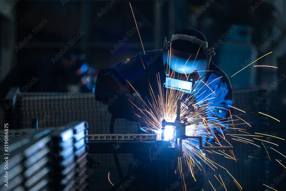 钢铁焊接厂穿着工业制服和焊接铁面罩的工人，工业安全