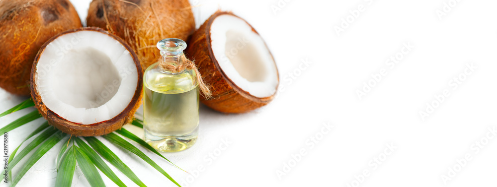 椰子油装在一个瓶子里，椰子和绿色棕榈树叶被隔离在白色背景上。Skinc