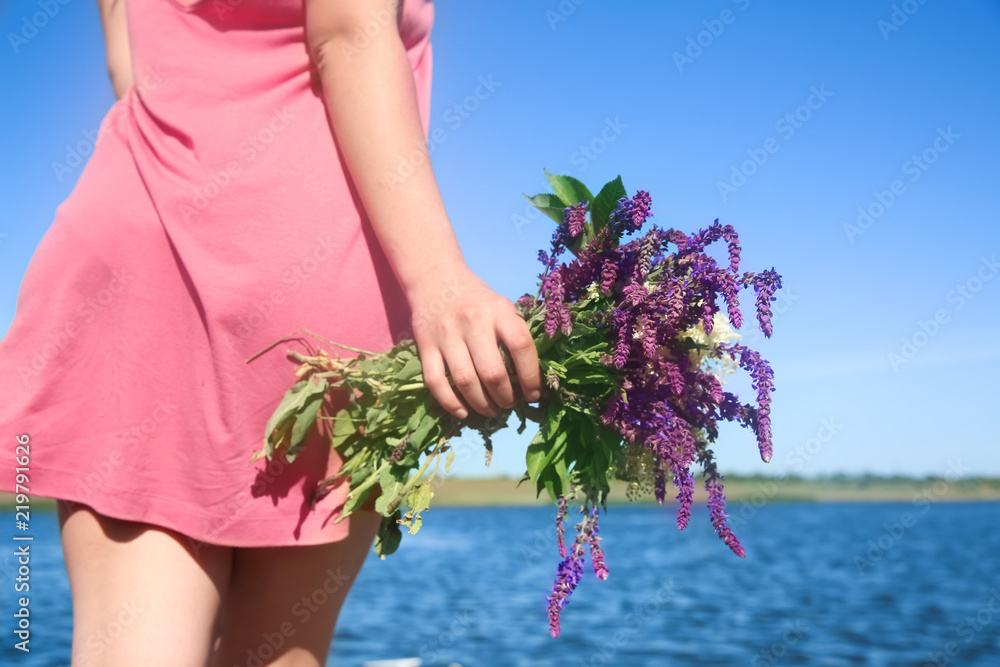 年轻女子在户外手持美丽的草地花束
