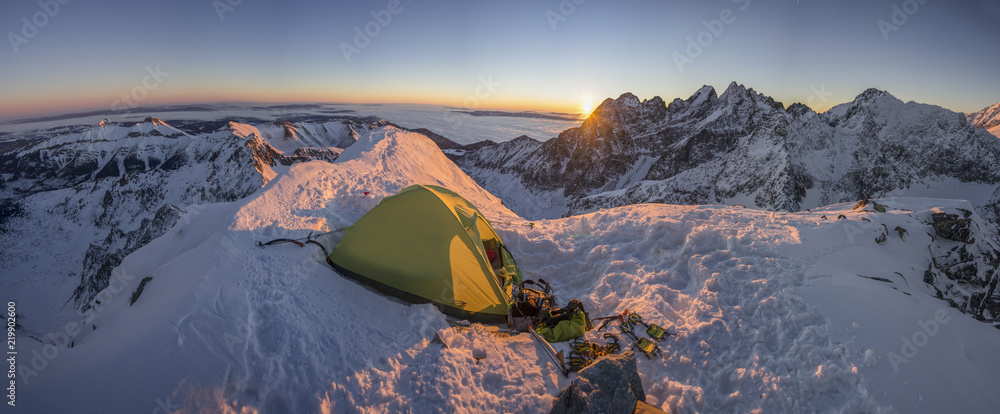 黄色帐篷搭在高山顶峰上。在冰雪覆盖的高山上露营