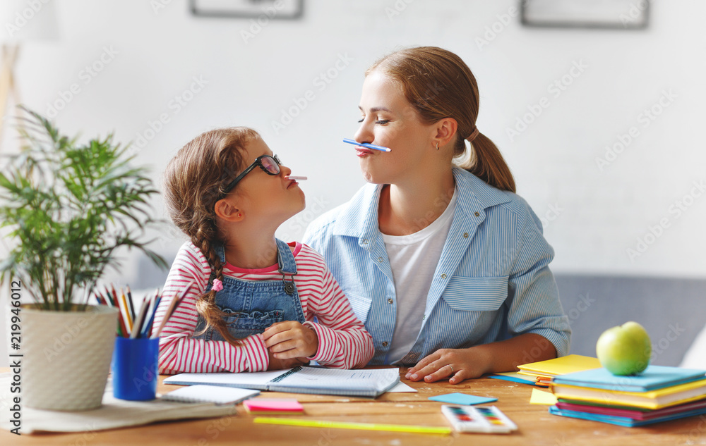 有趣的母亲和孩子女儿做家庭作业写作和阅读