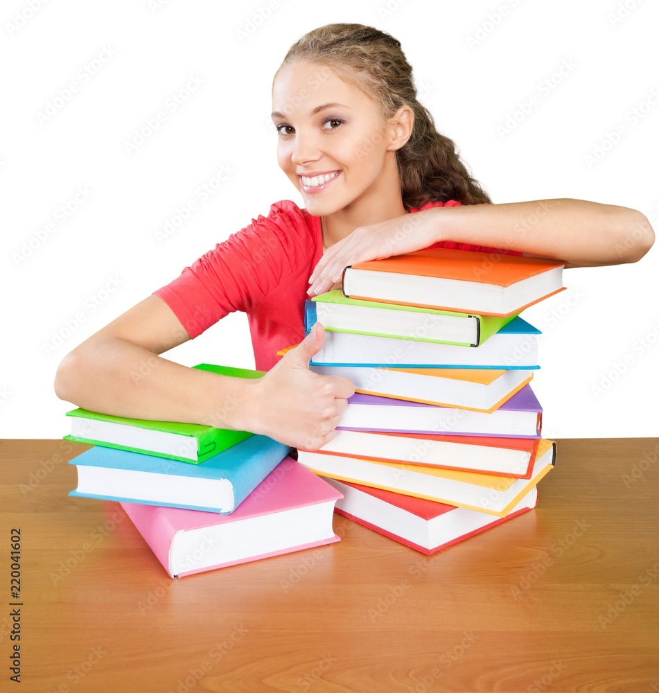 友好的年轻女孩拿着书和拇指坐在桌子后面