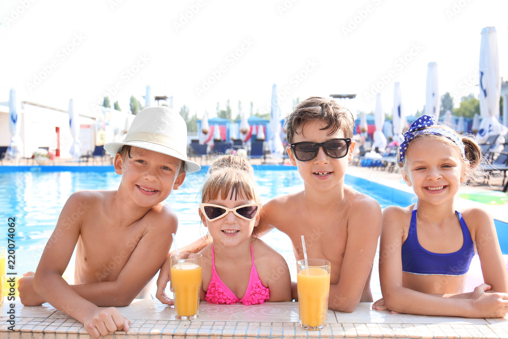 夏日泳池里带着几杯果汁的可爱孩子