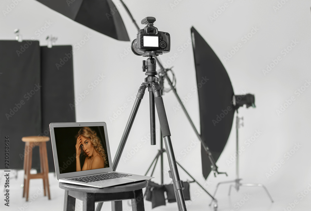 Stool with laptop and camera on tripod in modern photo studio