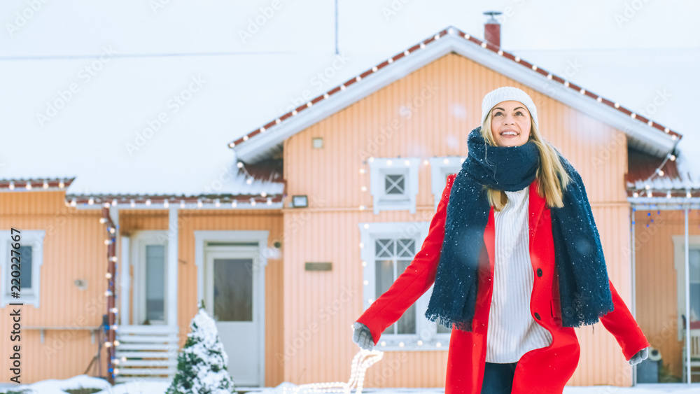 美丽的年轻微笑的女人在冬日向天空举起她的手。穿着红色外套和Sc的女孩