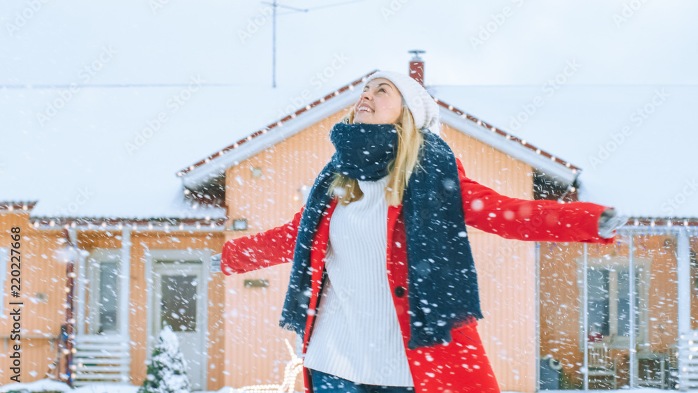 一位身穿红色外套、头戴围巾的年轻金发女子在后院散步跳舞的肖像