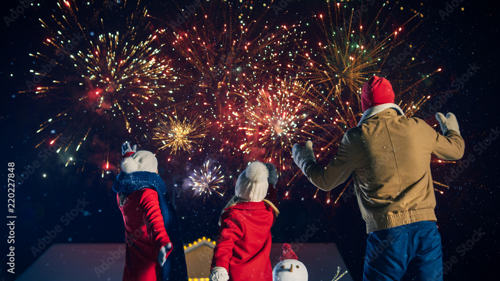 新年快乐，年轻的三口之家站在前院看美丽的火焰