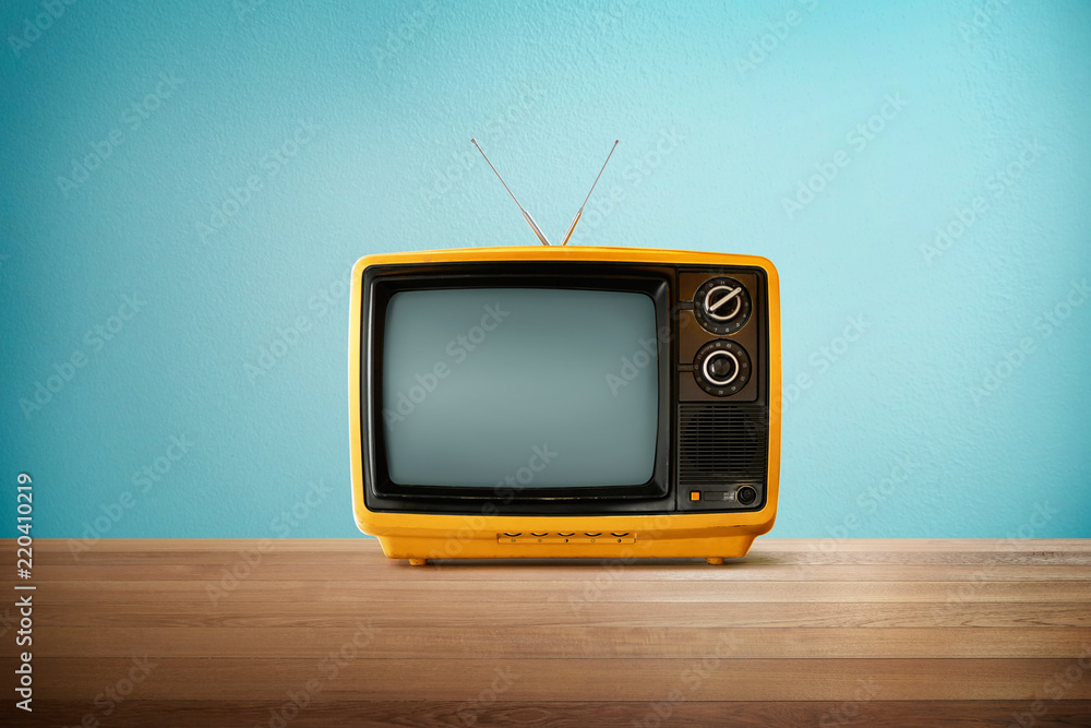 黄橙色老式复古电视，木质桌子，薄荷蓝色背景。