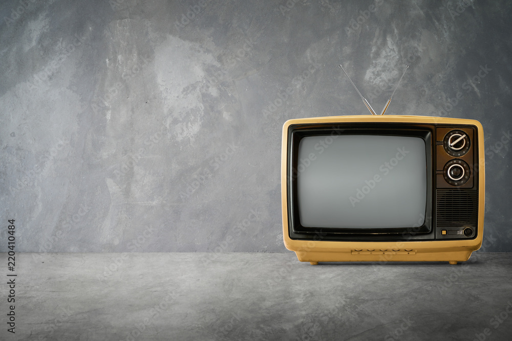 背景水泥桌上的黄橙色老式复古电视。