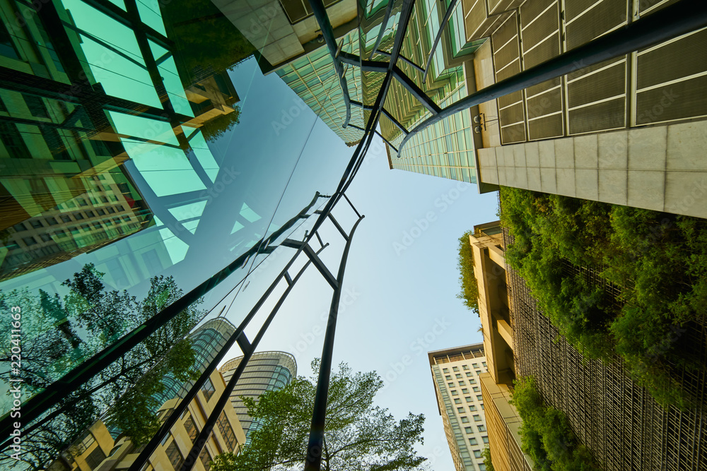 现代玻璃建筑和绿色的低角度拍摄，背景是晴朗的天空。