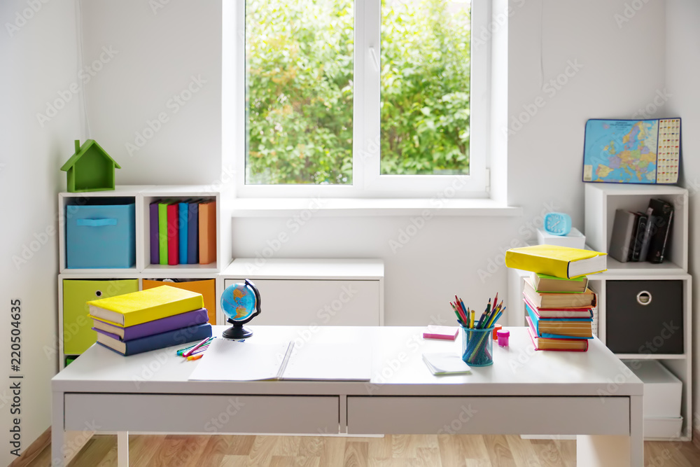彩色儿童房，白色墙壁和家具。家里有窗户的桌子