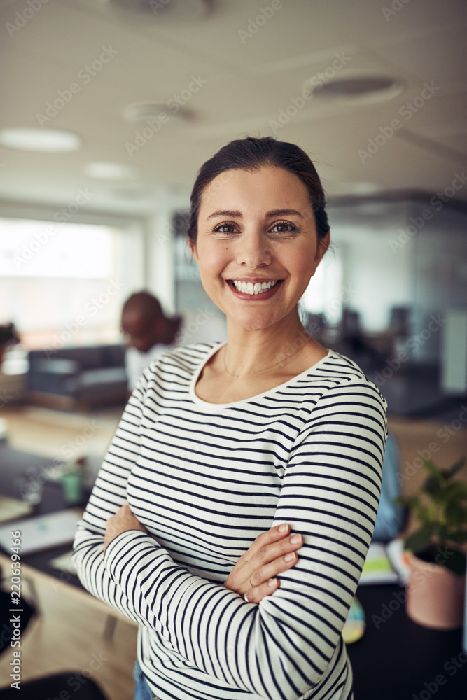 Smiling businesswoman standing with her arms crossed in an offic