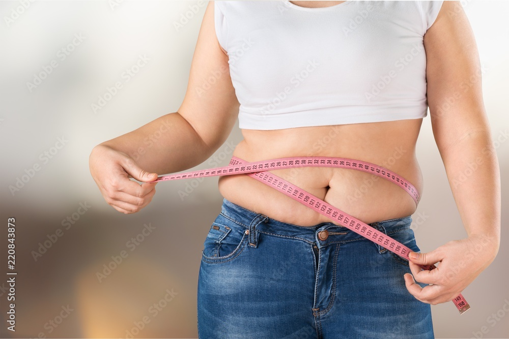 超重，胖女人在后台测量她的肚子