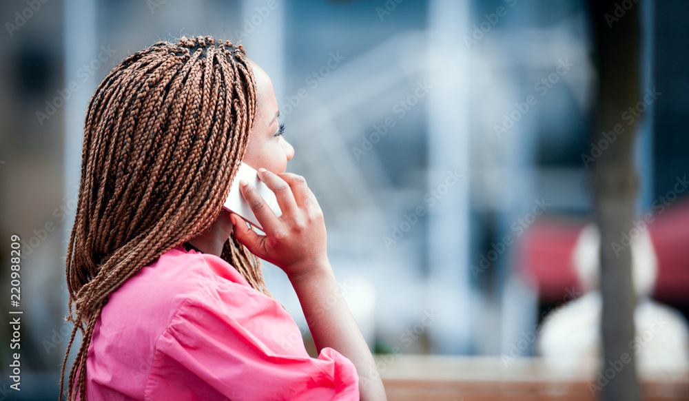 非洲女孩在城市街道上用智能手机户外聊天