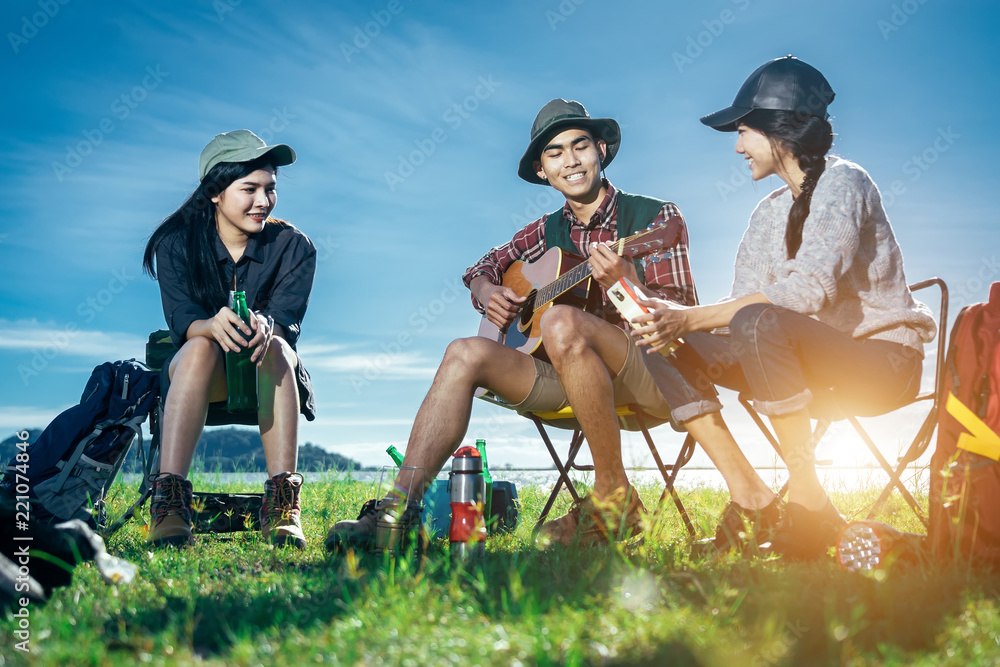 一群亚洲朋友坐在椅子上，唱歌，弹吉他，喝啤酒和哇