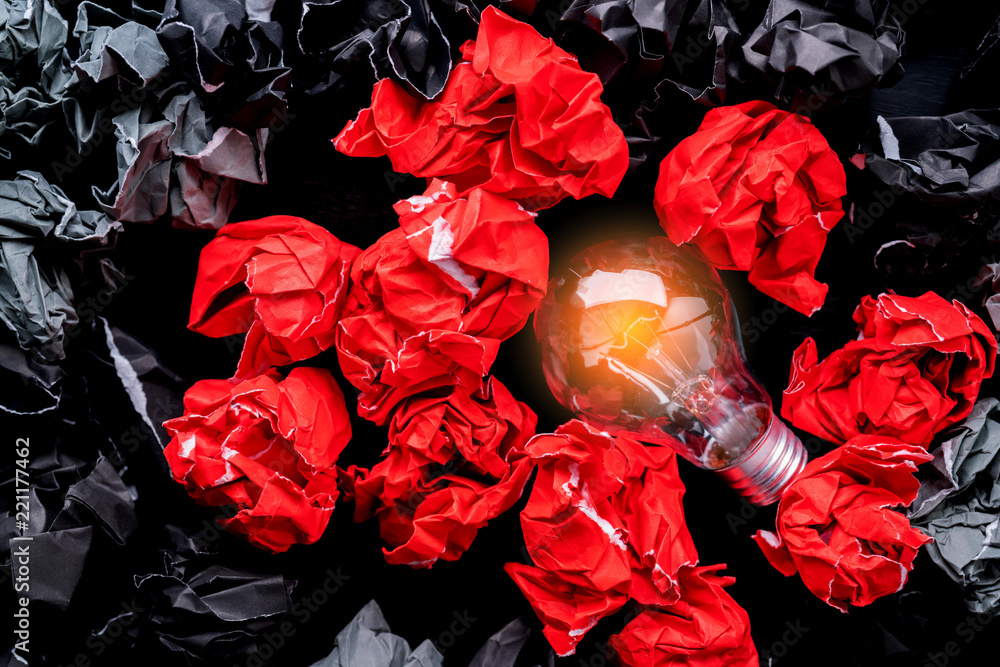 用灯泡和黑色和红色纸张揉皱的垃圾球创造创意概念