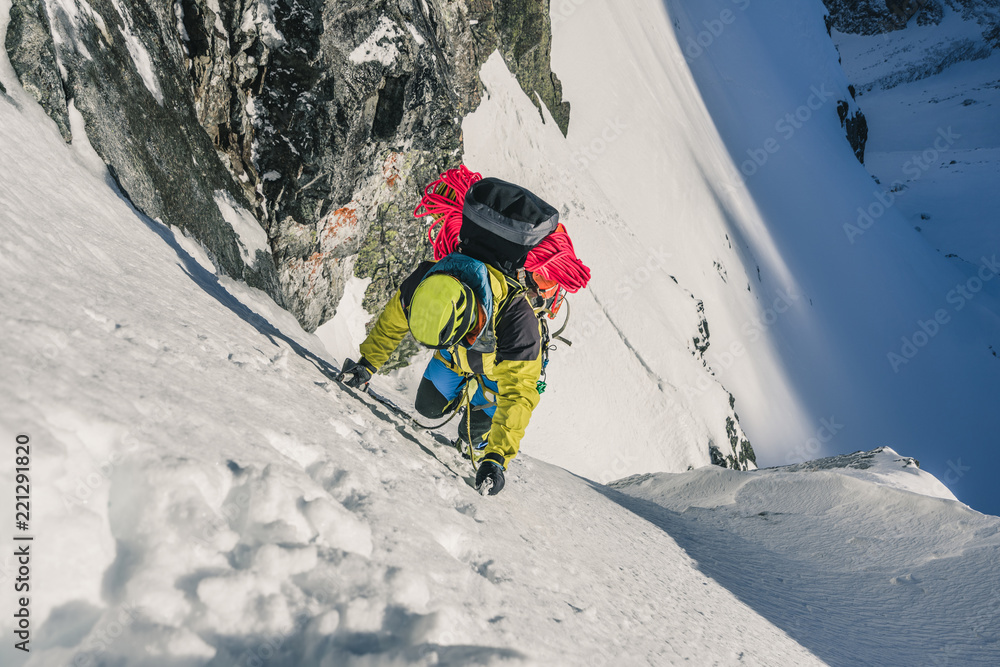 An alpinist climbing steep ice wall. A winter alpine ascent in alpine landscape. Adventure and extre