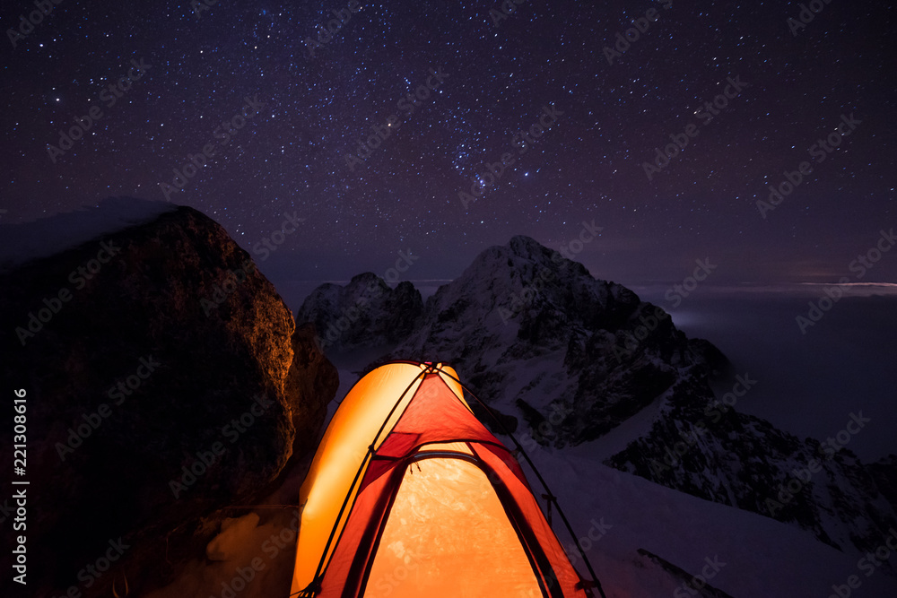 Orange tent under starry sky and milky way. Extreme and adventure winter camping under the stars in 