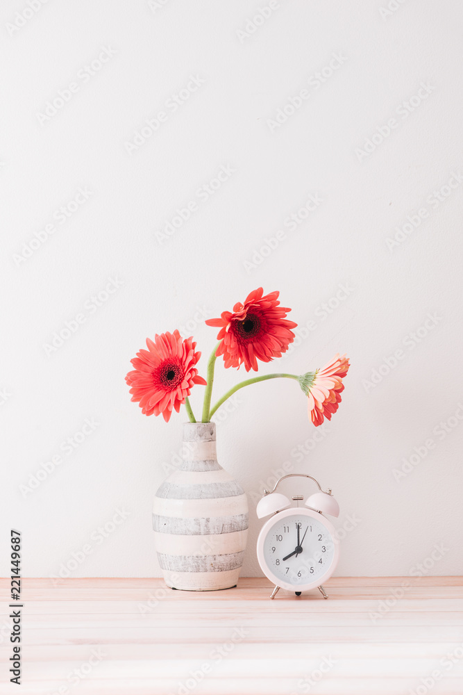 白色壁柜上的鲜花和闹钟