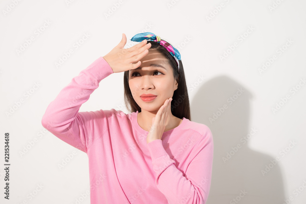 一个美丽的亚洲女孩的肖像，用明亮的阳光遮住脸。一个穿着粉色连衣裙的女人