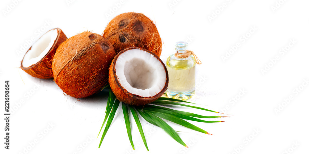 Coconut oil in a bottle with coconuts and green palm tree leaf isolated on a white background. Skinc