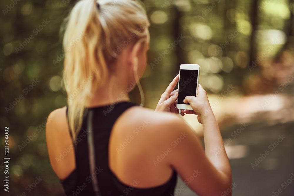 站在森林里拿着手机的运动女性