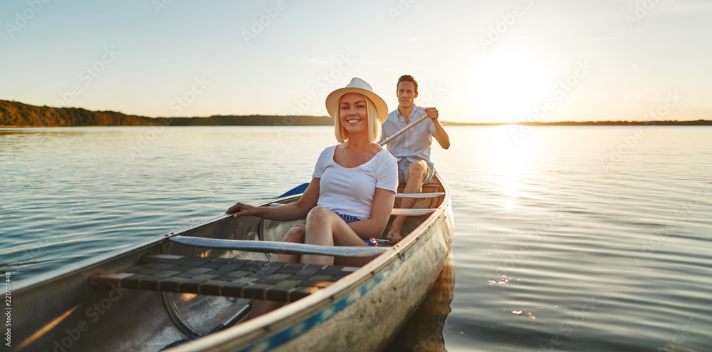 微笑的年轻夫妇在夏天一起在湖上划独木舟