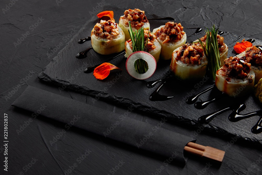 美味的寿司卷，在石板和筷子上放上奶油鳗鱼和泡菜蛋黄酱