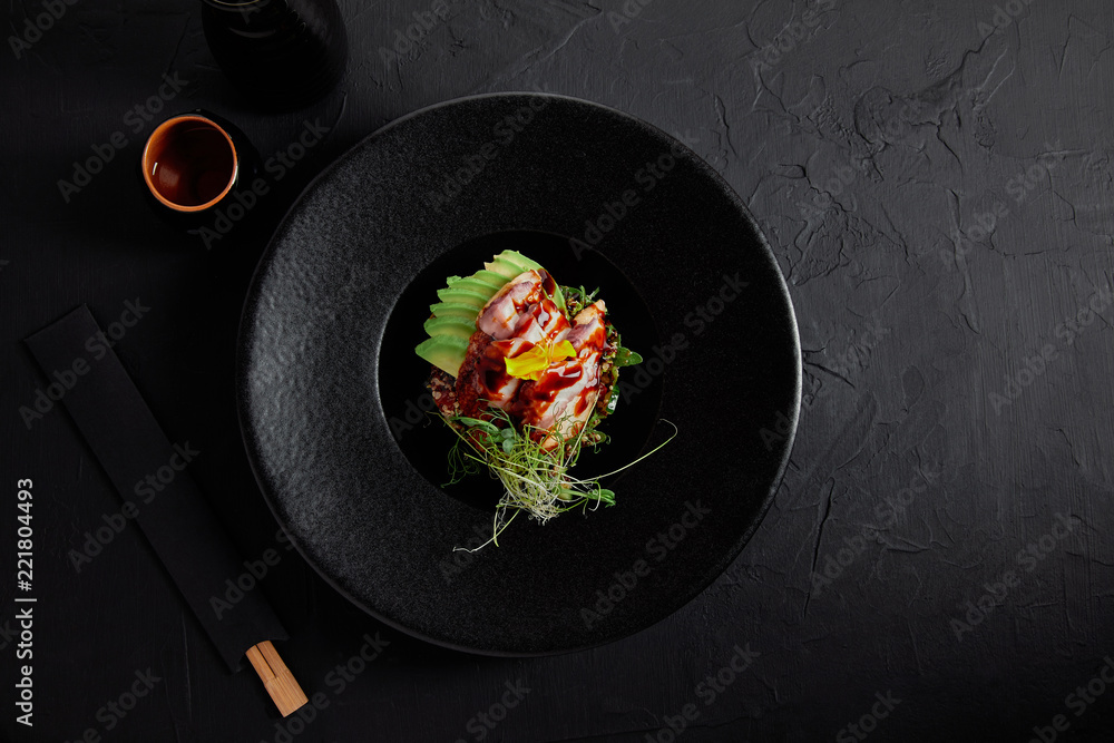 黑色盘子里有海鲜、鳄梨和香草的美味日本传统菜肴俯视图