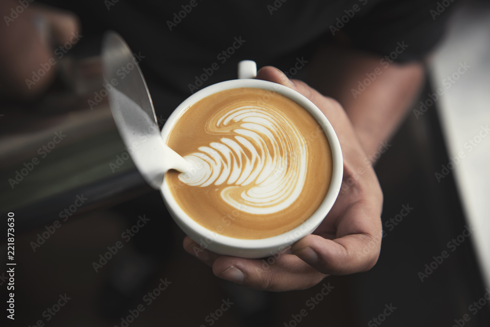 咖啡师在咖啡馆用泡沫咖啡杯制作拿铁或卡布奇诺艺术。