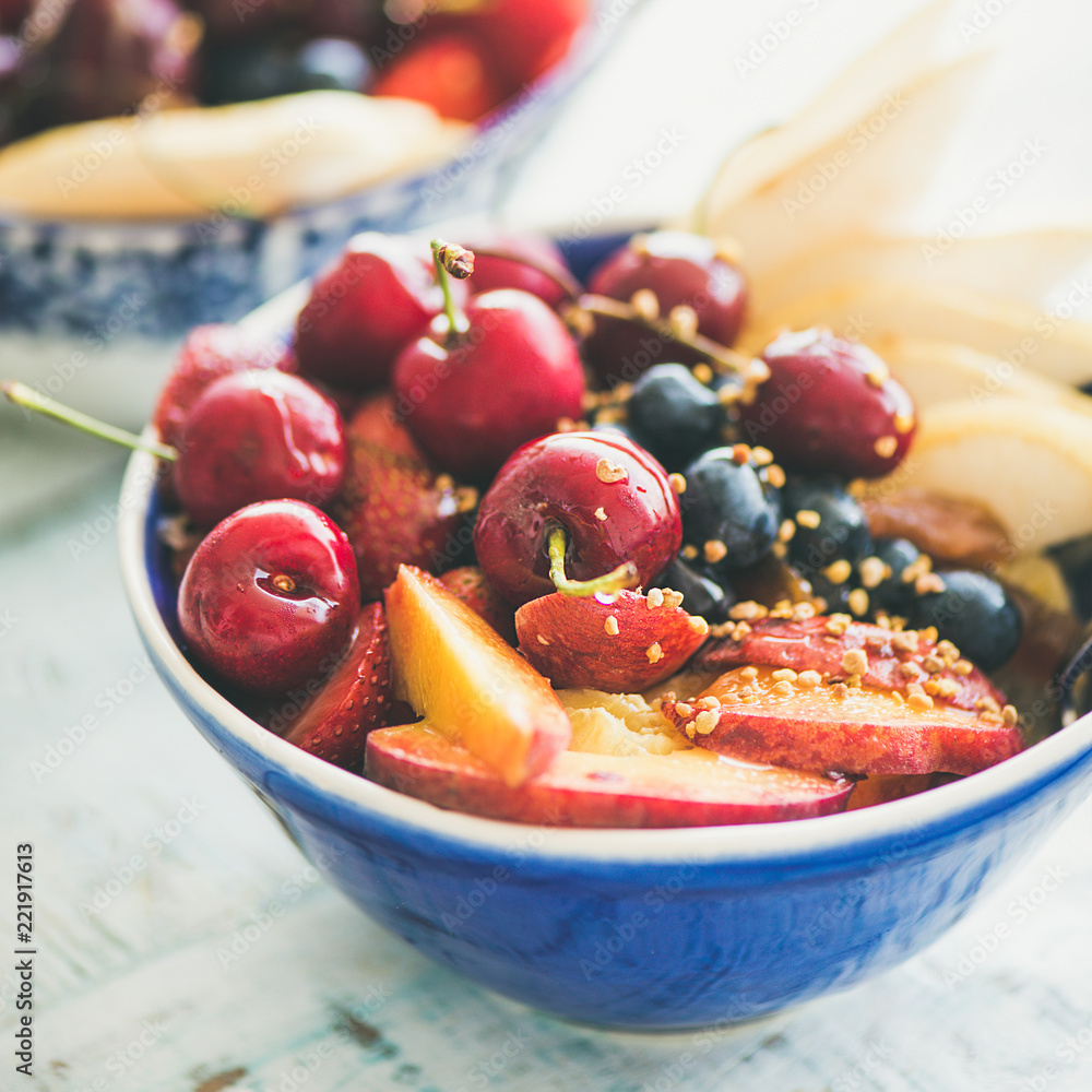 健康的冰沙碗，以新鲜水果和浆果、蜂花粉和蜂蜜为蓝桌背景